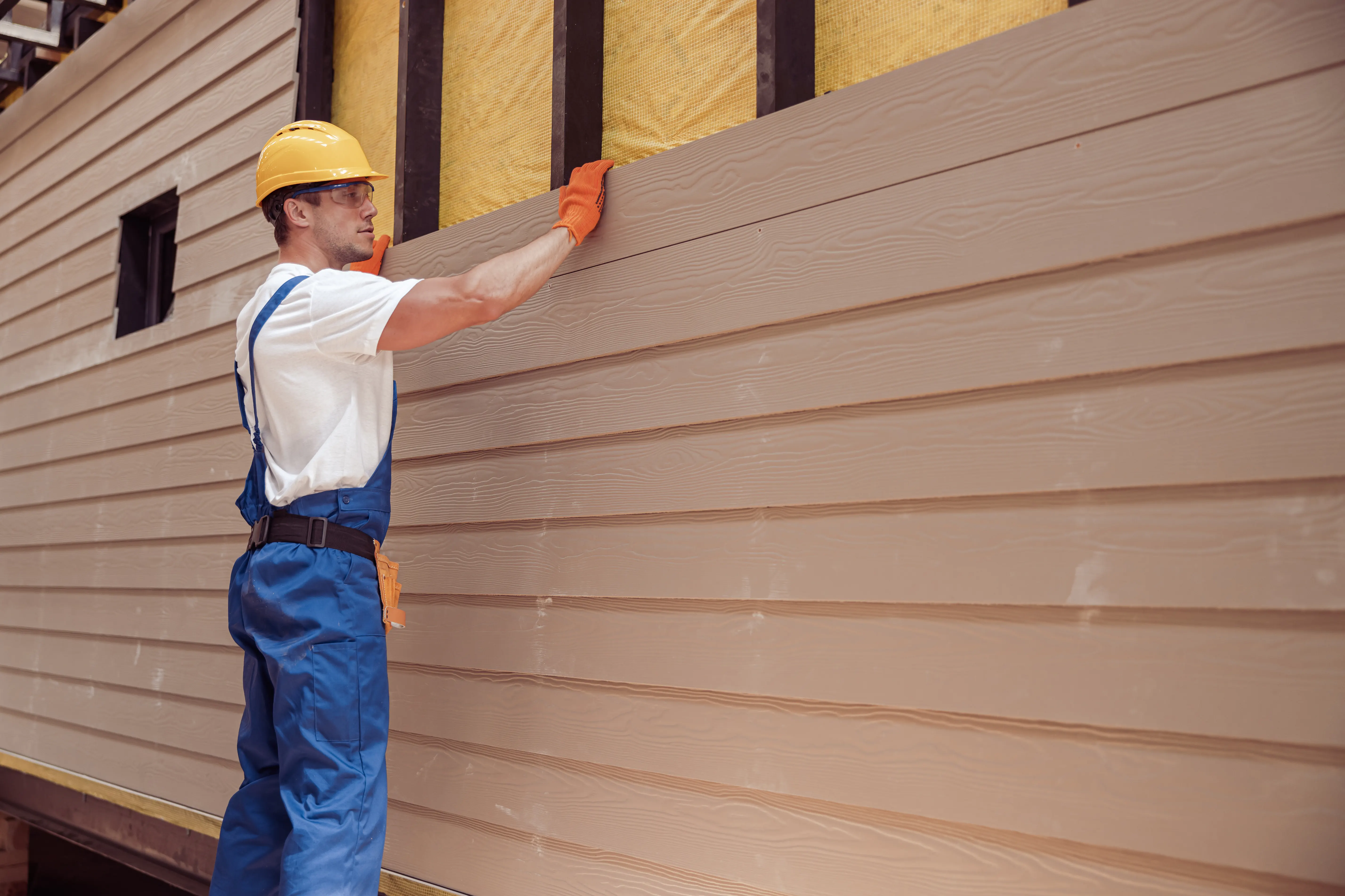 A man attaching light siding to a house